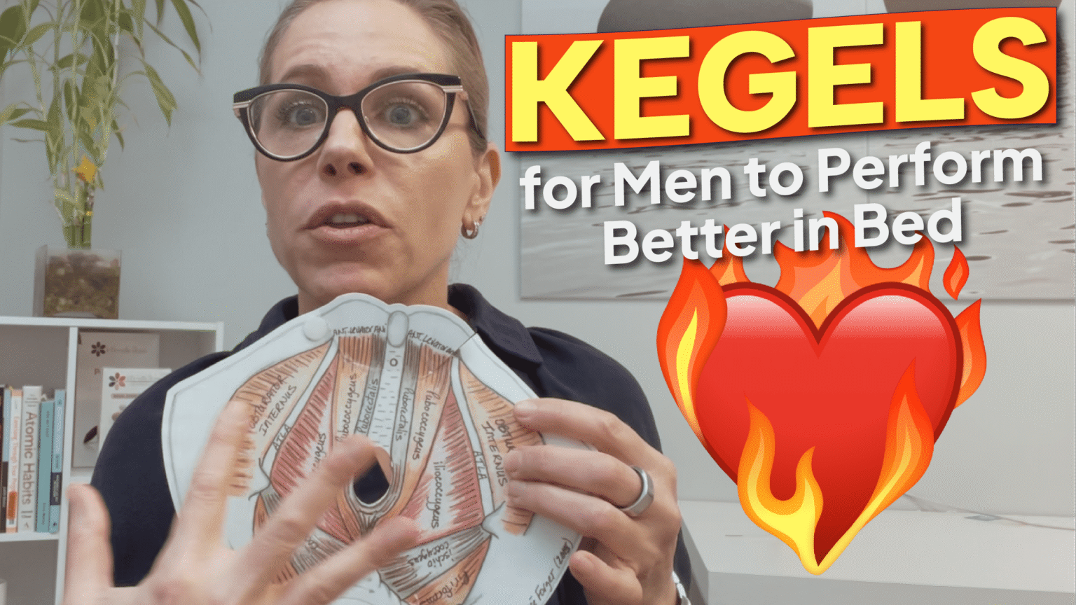 A person holds a pelvic anatomy model in an office setting with bookshelves and a plant in the background. Text overlay reads: "KEGELS for Men to Perform Better in Bed" in bold yellow and white on a red background, accompanied by a red heart with orange flames.